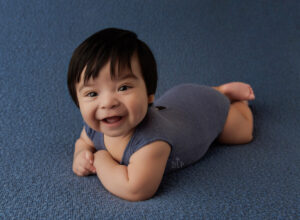 Experience Austin Baby Photography little boy laying on tummy wearing blue outfit smiling