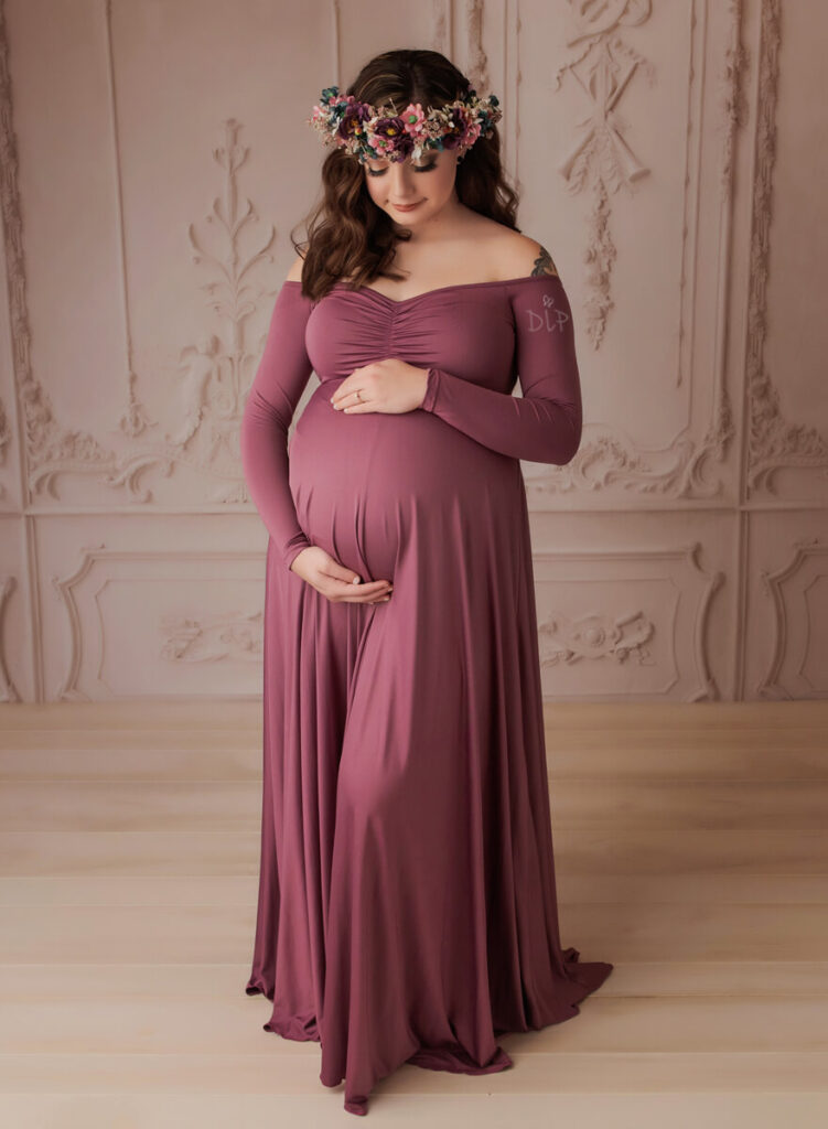 Austin Maternity Photographer expecting mom looking at belly in mauve gown
