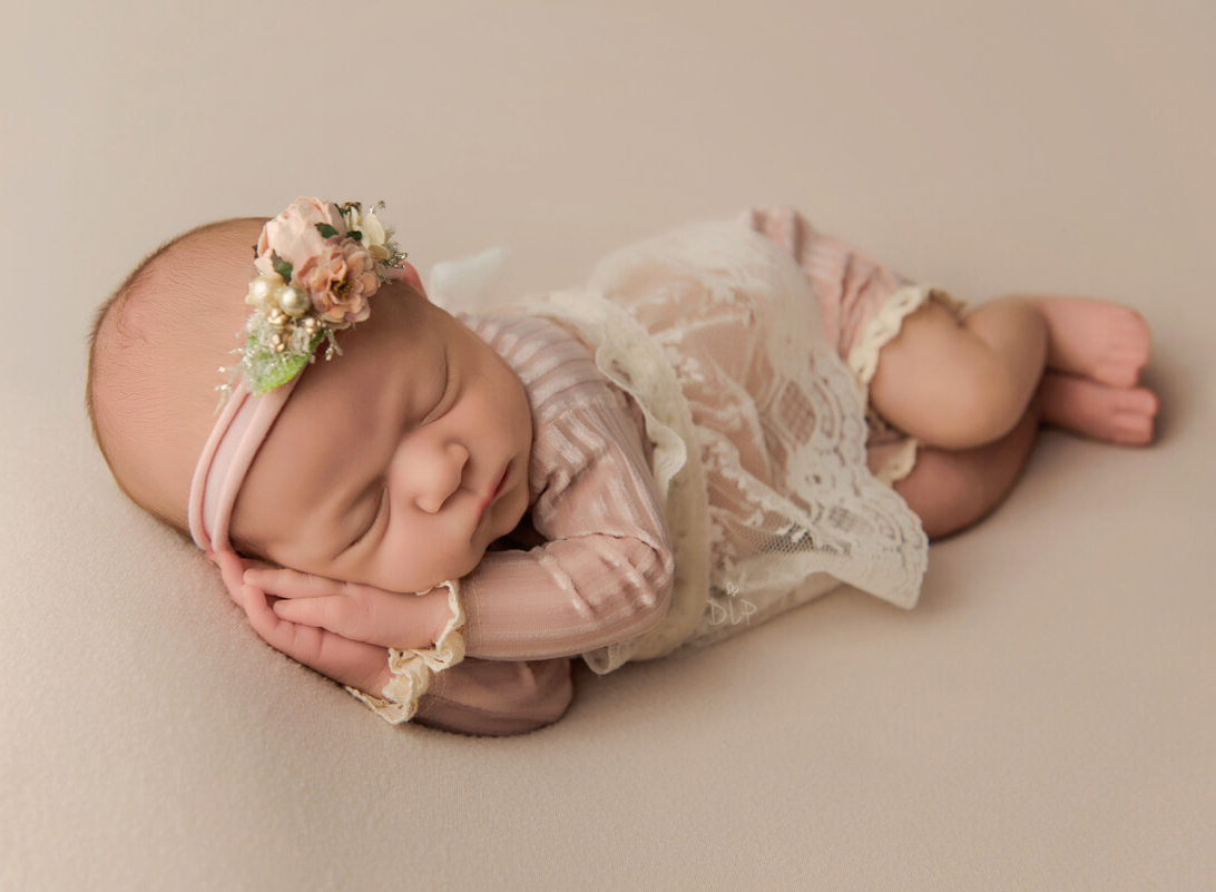 Austin Newborn Photographer baby girl in pink outfit on cream fabric