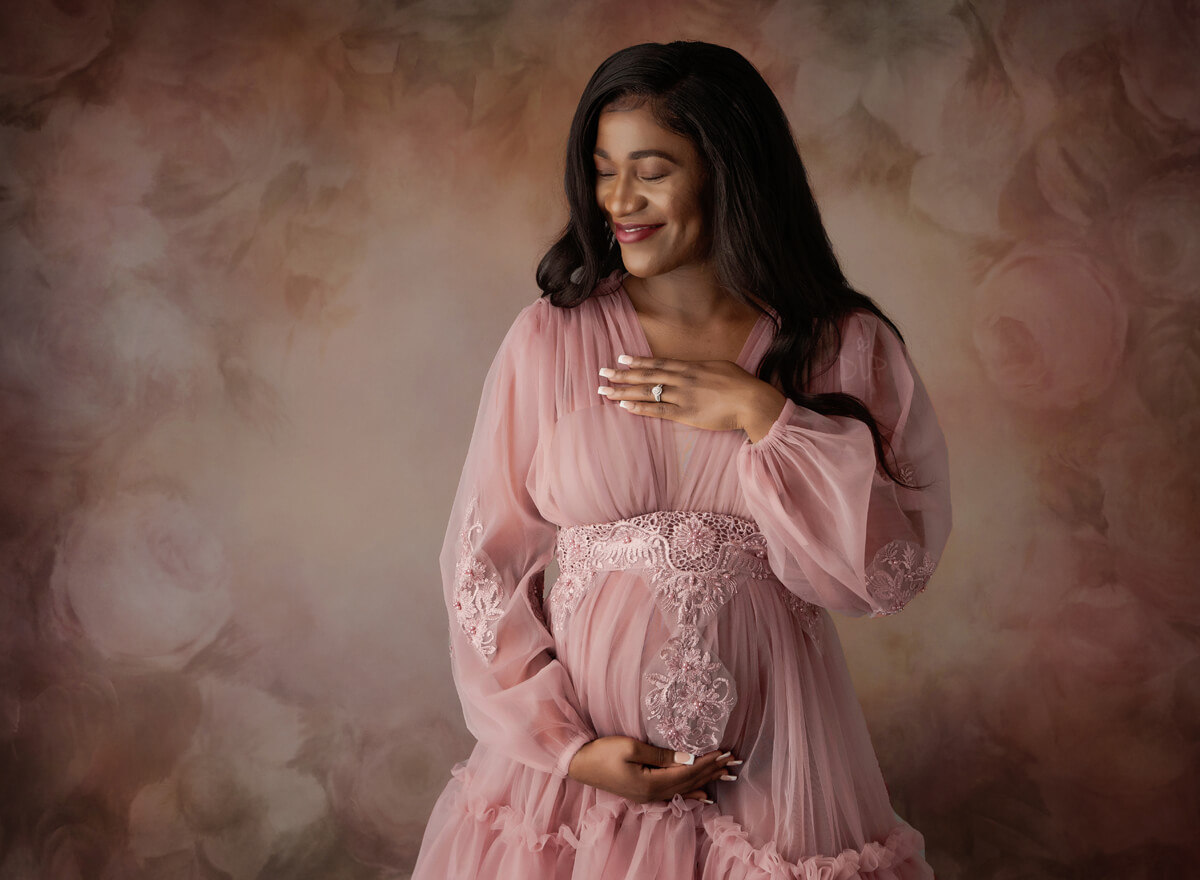 Austin Maternity Photographer expecting mom posing in pink gown with floral background