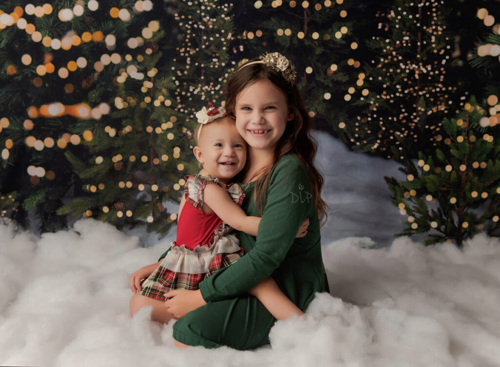 Experience Austin Baby Photography sisters sitting together on Christmas tree set