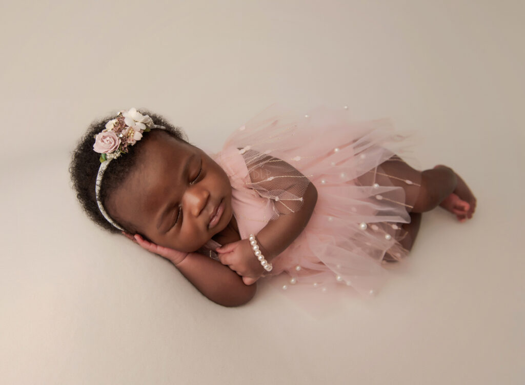 Austin Newborn Photographer baby girl in pink outfit on cream fabric